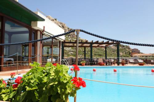 a swimming pool with red flowers next to a building at Hotel Miralonga in La Maddalena