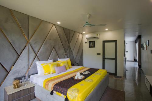 a bedroom with a large bed with yellow pillows at Elivaas 5 BHK with Pool, Tents & Pond - Kaimalgarh Farmstay in Bhundsi