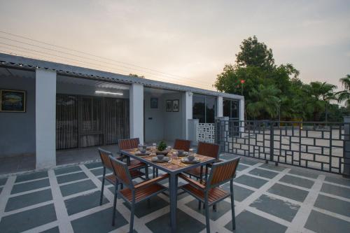 a dining table and chairs on a patio at Elivaas 5 BHK with Pool, Tents & Pond - Kaimalgarh Farmstay in Bhundsi