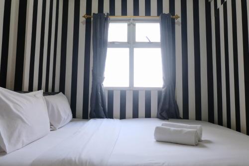a bedroom with a white bed with a window at Good Deal 2BR at 16th Floor Suites @Metro Apartment By Travelio in Bandung