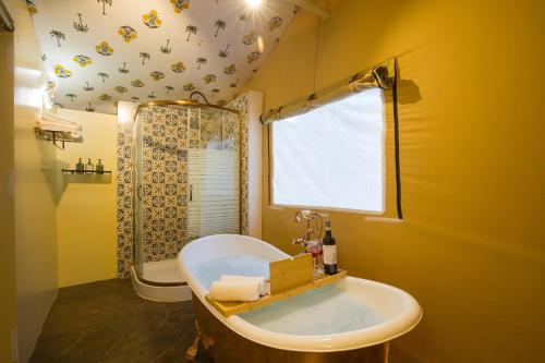 a bathroom with a tub and a shower and a sink at Elivaas 5 BHK with Pool, Tents & Pond - Kaimalgarh Farmstay in Bhundsi