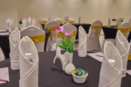a table with white chairs and a vase with flowers at Grand Continent Mysore A Sarovar Portico Affiliate Hotel in Mysore