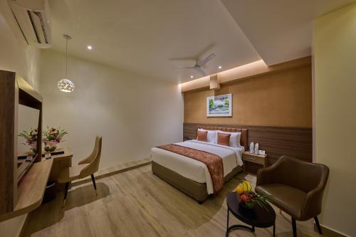 a hotel room with a bed and a chair at Grand Continent Mysore A Sarovar Portico Affiliate Hotel in Mysore