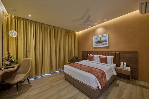 a hotel room with a bed and a desk and a desk at Grand Continent Mysore A Sarovar Portico Affiliate Hotel in Mysore