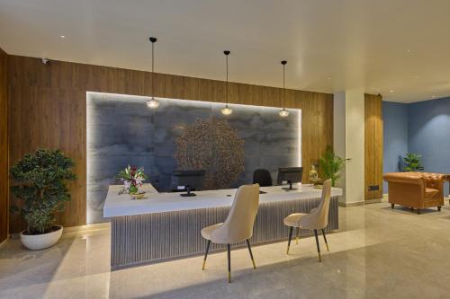 a lobby with a reception desk with two chairs and avertisement at Grand Continent Mysore A Sarovar Portico Affiliate Hotel in Mysore