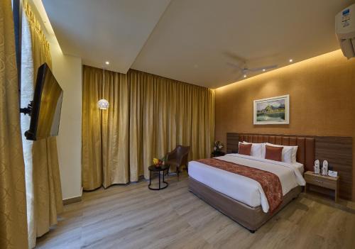 a hotel room with a bed and a television at Grand Continent Mysore A Sarovar Portico Affiliate Hotel in Mysore