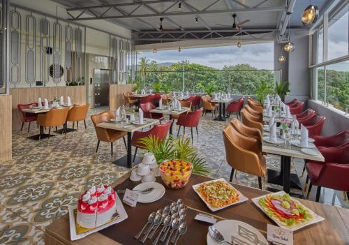 a restaurant with tables and chairs with food on them at Grand Continent Mysore A Sarovar Portico Affiliate Hotel in Mysore
