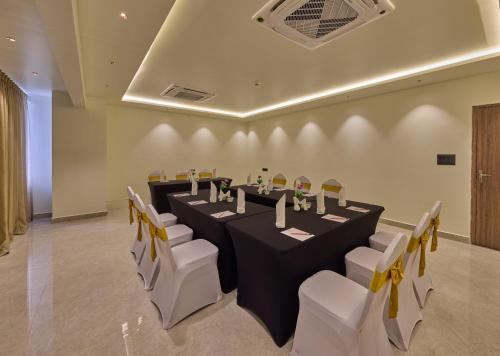 a conference room with a long table and white chairs at Grand Continent Mysore A Sarovar Portico Affiliate Hotel in Mysore