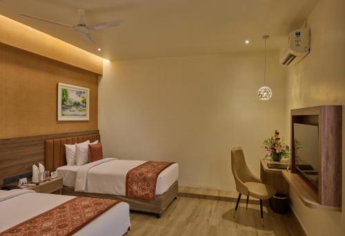 a hotel room with two beds and a desk at Grand Continent Mysore A Sarovar Portico Affiliate Hotel in Mysore