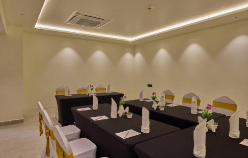 a room with black tables and chairs with flowers on them at Grand Continent Mysore A Sarovar Portico Affiliate Hotel in Mysore