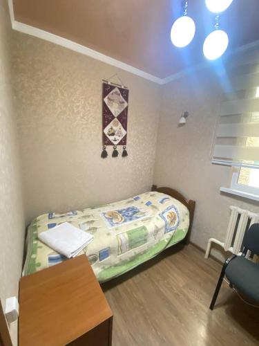 a small bedroom with a bed and a desk at Tian-Shan Guest House in Balykchy