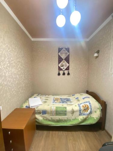 a small bedroom with a bed and a table at Tian-Shan Guest House in Balykchy