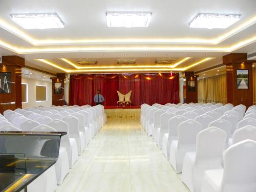 a room with white chairs and a man in a stage at Hotel Sri Sierra in Chik Ballāpur