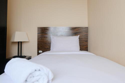 a white bed with a wooden headboard in a room at Best Location 2BR at Braga City Walk Apartment By Travelio in Bandung