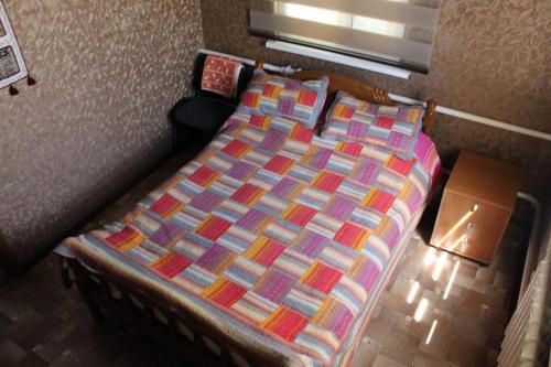 a bedroom with a bed with a colorful comforter at Tian-Shan Guest House in Balykchy