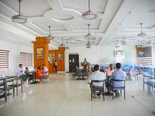a group of people sitting at tables in a restaurant at Hotel Sri Sierra in Chik Ballāpur
