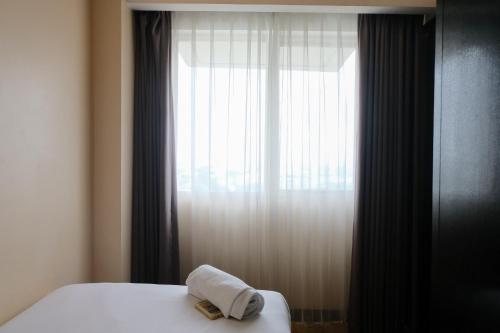 a bed with a towel on it next to a window at Best Location 2BR at Braga City Walk Apartment By Travelio in Bandung