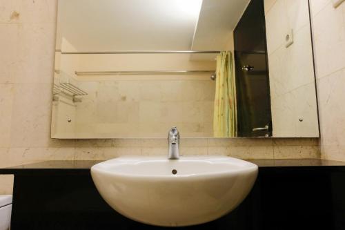 a white sink in a bathroom with a mirror at Best Location 2BR at Braga City Walk Apartment By Travelio in Bandung