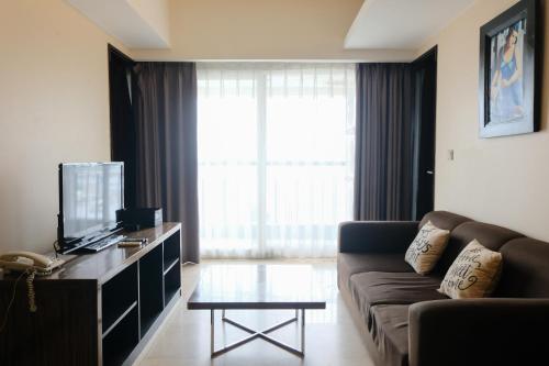a living room with a couch and a tv at Best Location 2BR at Braga City Walk Apartment By Travelio in Bandung