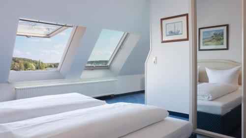 two beds in a room with two windows at Hotel Am Yachthafen in Waren