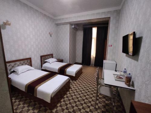 a hotel room with two beds and a television at Yulduz Hotel in Andijan