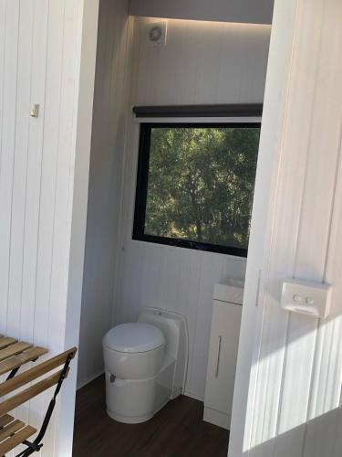 a small bathroom with a toilet and a window at Sandy Strait Shack by Tiny Away in Urangan