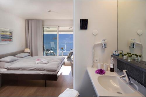 a bedroom with a bed and a tub and a sink at Hotel Stella SA in Locarno