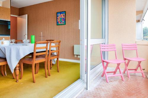 une salle à manger avec des chaises roses et une table dans l'établissement À 200m de la plage, appartement vue mer pour 4, à Bénodet
