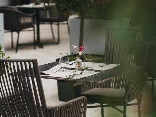 a table with glasses and a vase of flowers on it at Hotel Eibl-Brunner 4-Sterne-Superior in Frauenau