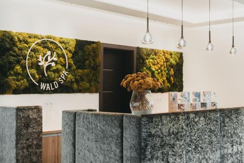 a lobby with a green wall with a vase of flowers at Hotel Eibl-Brunner 4-Sterne-Superior in Frauenau