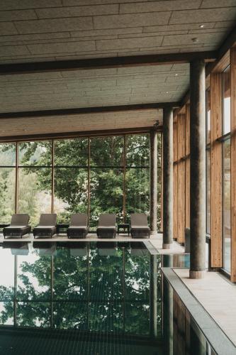 a room with a pool with chairs and windows at Hotel Eibl-Brunner 4-Sterne-Superior in Frauenau
