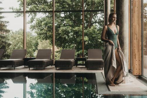 a woman in a green dress standing next to a swimming pool at Hotel Eibl-Brunner 4-Sterne-Superior in Frauenau