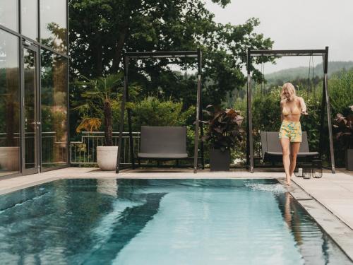 a woman standing next to a swimming pool at Hotel Eibl-Brunner 4-Sterne-Superior in Frauenau