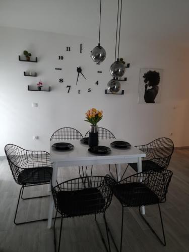 a white table with chairs and a clock on a wall at Presidenziale in Stara Pazova
