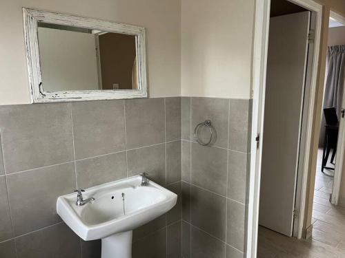 ein Badezimmer mit Waschbecken und Spiegel in der Unterkunft Forest Drive Cottage in Kloof