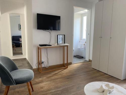 un salon avec une chaise et une télévision murale dans l'établissement Appartement avec terrasse et vue mer, à Calcatoggio
