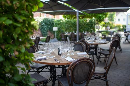 a wooden table with wine glasses on a patio at The Originals Boutique, La Maison Rouge, Lens Ouest in Noeux-les-Mines