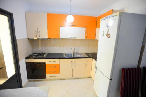Apartment Rivaaa في بيرات: مطبخ بخزائن برتقالية وبيضاء وحوض غسيل