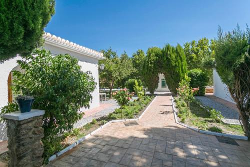 a courtyard with a garden with flowers and trees at Embrujo Andaluz Complejo Rural Órgiva in Órgiva