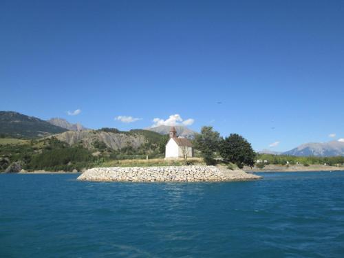 a small island with a church in the middle of the water at Le Chalet Pastorale Pied Des Pistes in Les Orres