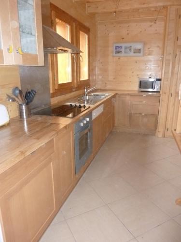 a kitchen with wooden cabinets and a stove top oven at Le Chalet Pastorale Pied Des Pistes in Les Orres