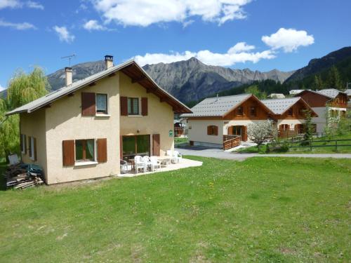 a house in a field with mountains in the background at Le Chalet Pastorale Pied Des Pistes in Les Orres