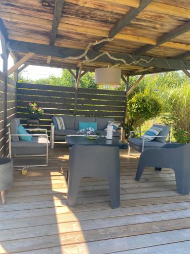 a patio with a table and chairs under a pergola at La Chaumeauniere in Aigrefeuille-dʼAunis