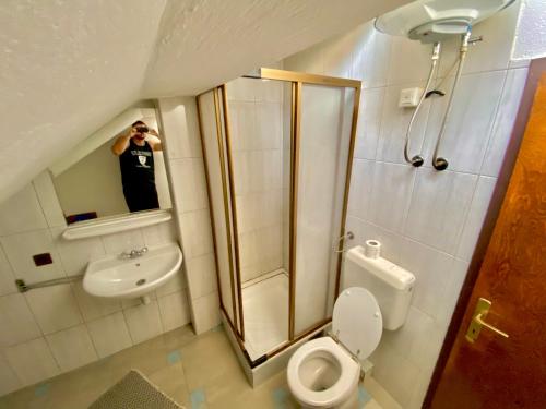 a man taking a picture of a bathroom with a toilet and shower at Apartman LITTLEHOME Travnik in Travnik