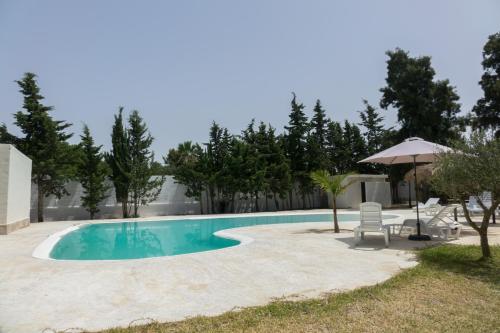 a swimming pool with two chairs and an umbrella at Chalet El Molino in Chiclana de la Frontera