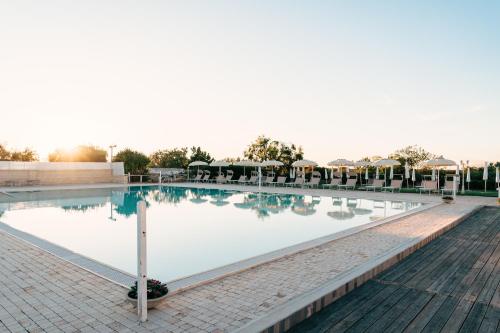 a swimming pool at a resort with tables and chairs at Zyra Garden Club in Acquaviva delle Fonti