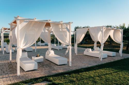an outdoor wedding with white chairs and a canopy at Zyra Garden Club in Acquaviva delle Fonti