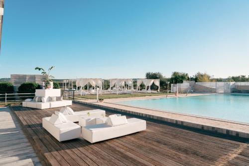 a pool with white furniture next to a swimming pool at Zyra Garden Club in Acquaviva delle Fonti