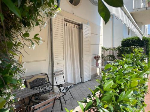 un patio con 2 sedie e una panca su un edificio di Appartamento IL GLICINE a piano terra zona tranquilla a due passi dal mare a Lido di Savio