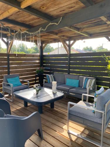 a patio with chairs and a table on a wooden deck at La Chaumeauniere in Aigrefeuille-dʼAunis